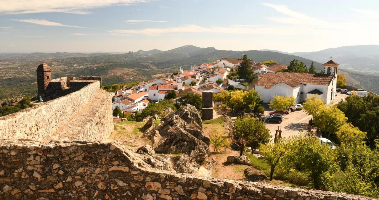 Blick auf das malerische Dorf Portalegre mit seinen weißen Häusern und roten Dächern, umgeben von einer alten Steinmauer und bergiger Landschaft.