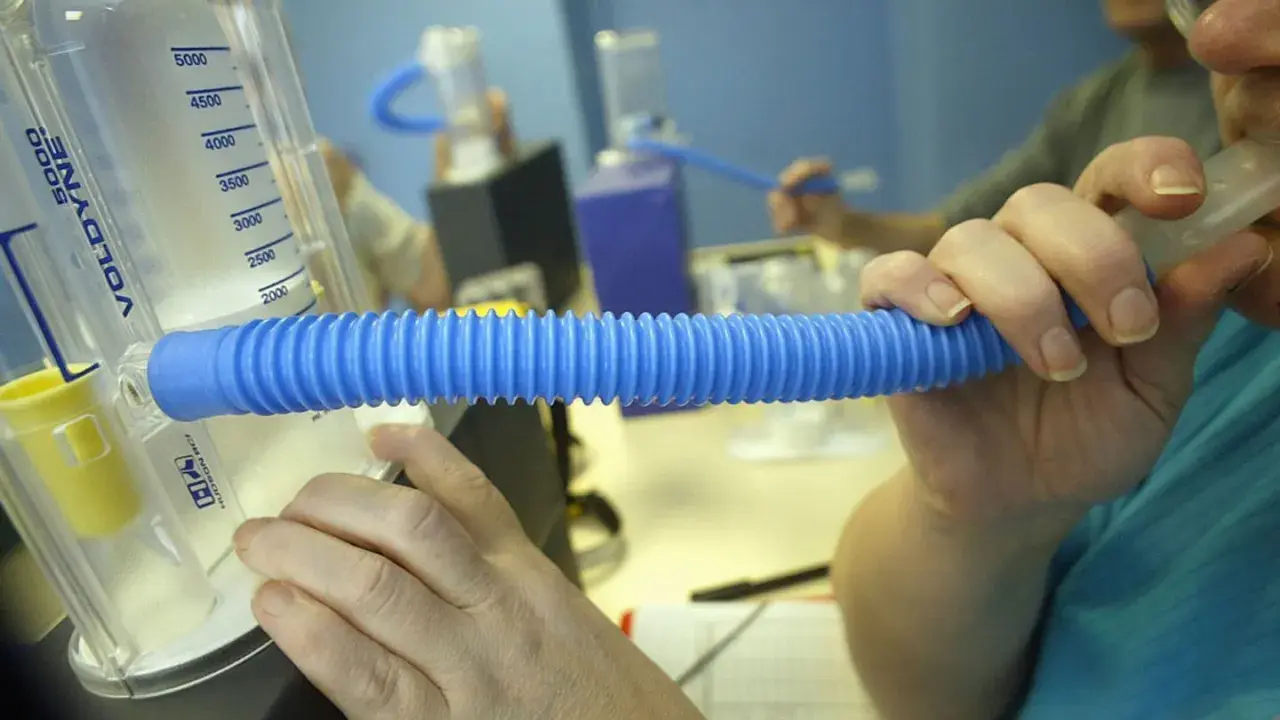 Person nutzt ein Spirometer für einen Lungenfunktionstest. Der Asthmaspray ist nicht sichtbar, aber das Gerät hilft bei der Diagnose.