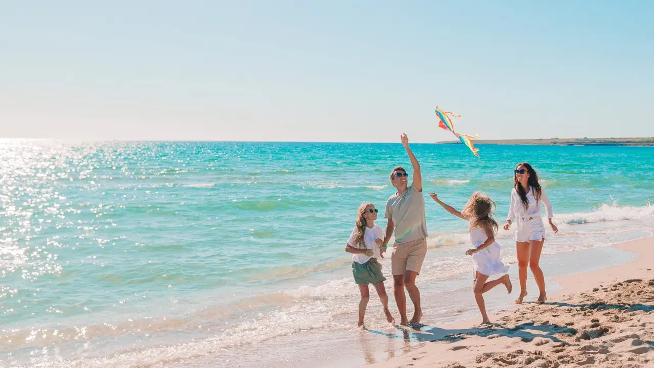 Rodzina puszcza latawiec na piaszczystej plaży. Piękne kąpieliska nad Bałtykiem zachęcają do zabawy.