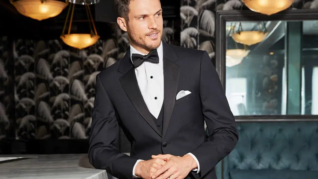 A man in a sharp tuxedo, perfect for any black tie event or formal occasion. He embodies the classic tuxedo dress code with a crisp white shirt and bow tie.