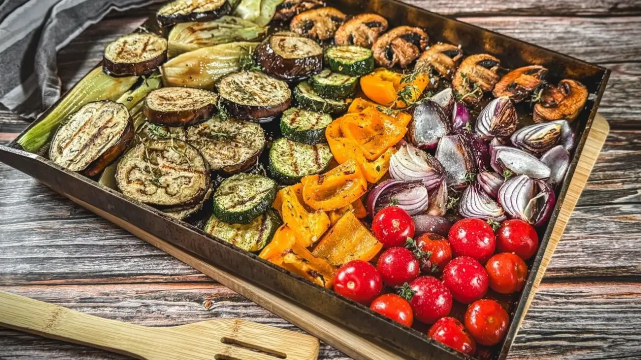 Buntes Gemüse wie Auberginen, Zucchini, Paprika, Zwiebeln und Tomaten auf einem Blech für ein köstliches vegetarisches Grillen.