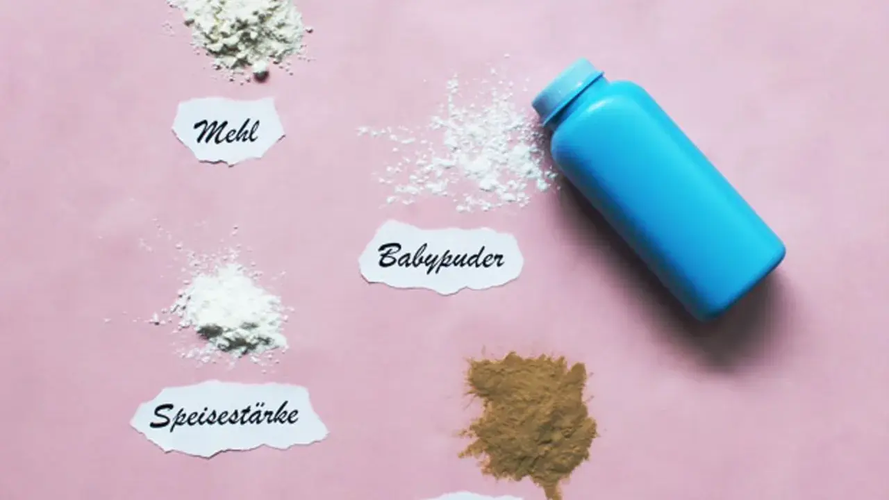 Blauer Behälter mit Babypuder, daneben Häufchen von Mehl, Speisestärke und Heilerde. Babypuder als trockenshampoo für schnelle Hilfe.