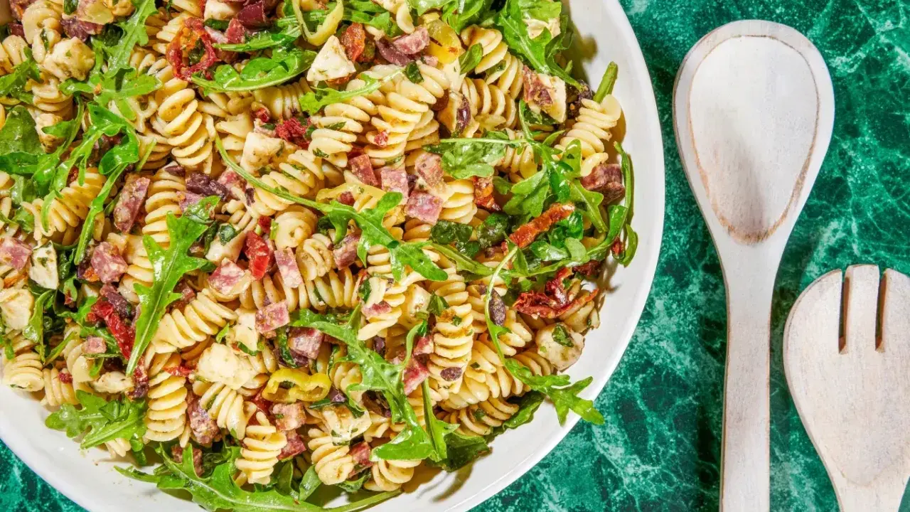 Pyszna sałatka z makaronem fusilli, rukolą, suszonymi pomidorami, oliwkami i kawałkami salami. Idealna na letnie dni.
