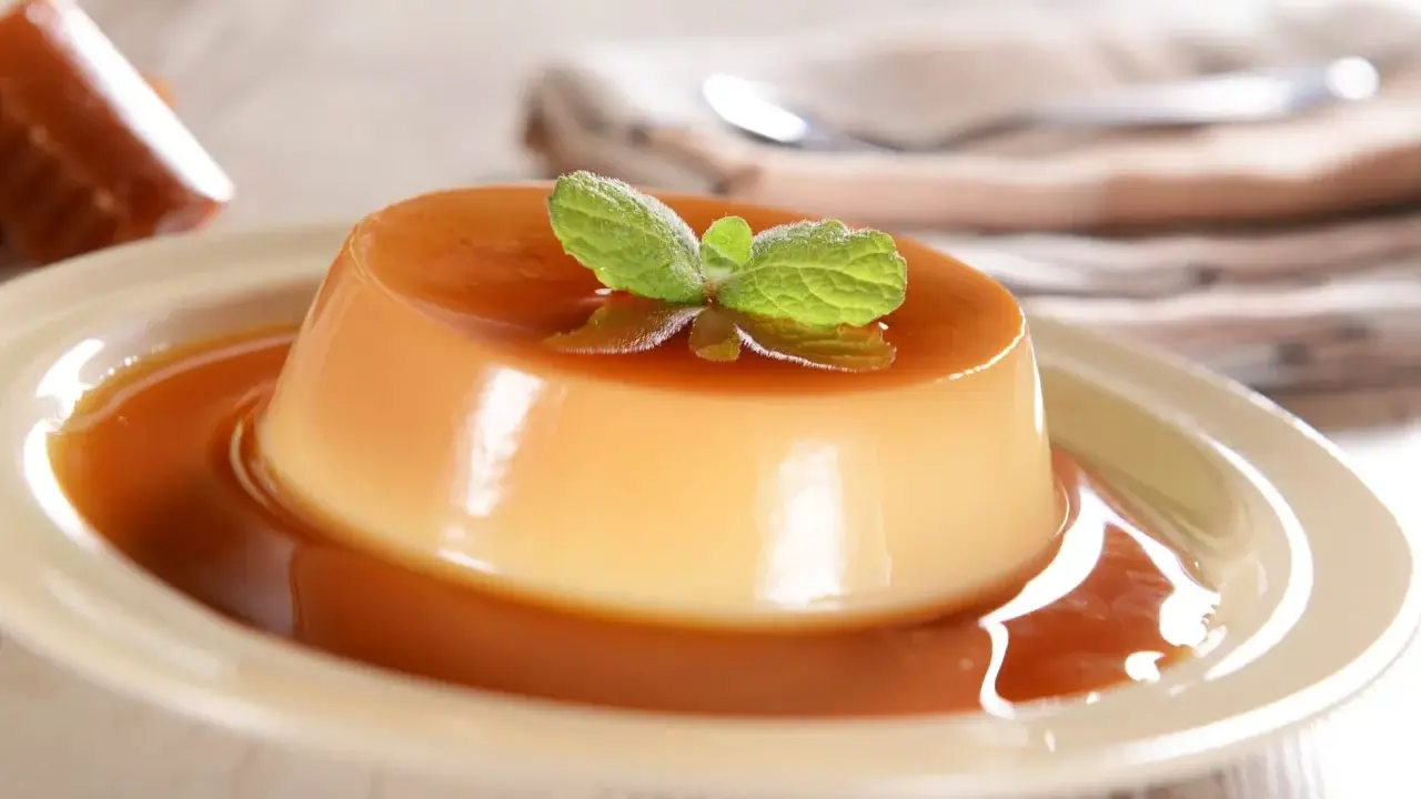 Un délicieux panna cotta caramel, nappé de sauce et garni d'une feuille de menthe. Un dessert onctueux et gourmand.