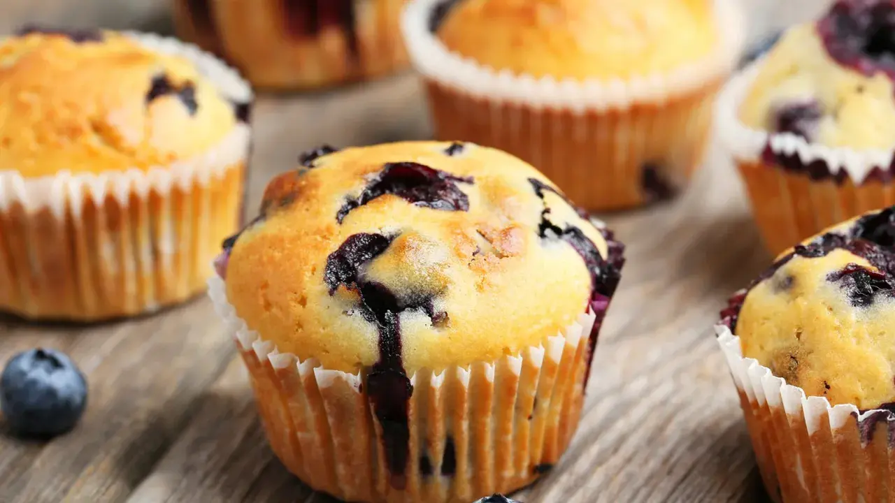 Saftige blaubeer muffins mit frischen Beeren auf rustikalem Holz.
