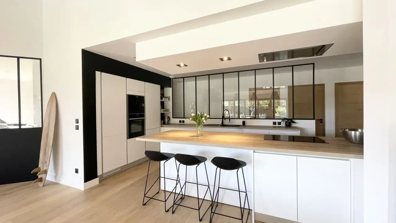 Cuisine moderne avec îlot central, plan de travail en bois et verrière industrielle. Une belle idée cuisine avec verriere pour un espace lumineux.