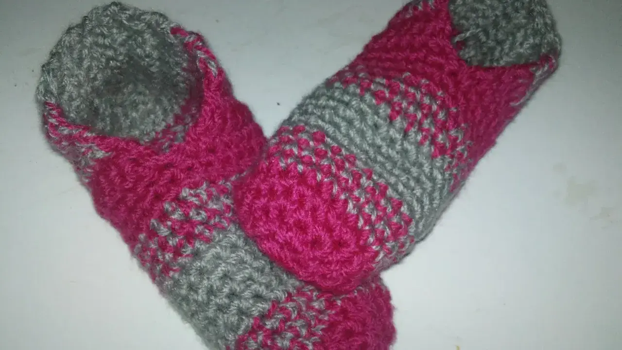 Ett par handvirkade tofflor i rosa och grått. Perfekta för mysiga hemmakvällar.