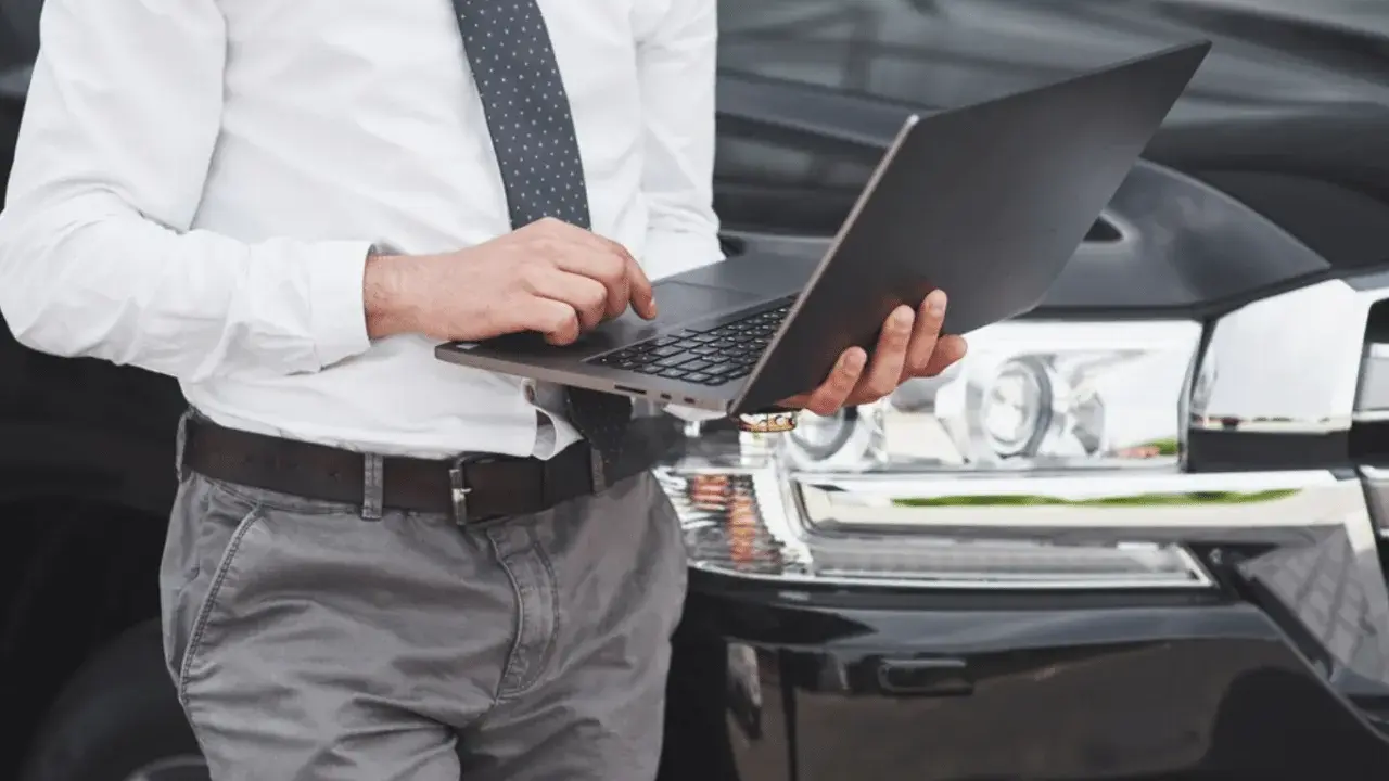 Mężczyzna w koszuli i krawacie sprawdza na laptopie, kiedy trzeba przerejestrować auto.