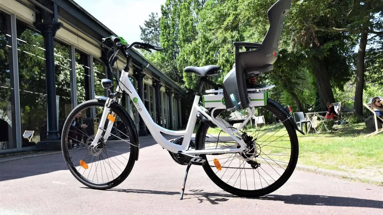 Vélo blanc avec siège enfant, prêt à rouler. Peut-on rouler avec un vélo électrique sans batterie ? Oui, mais ce sera plus difficile !