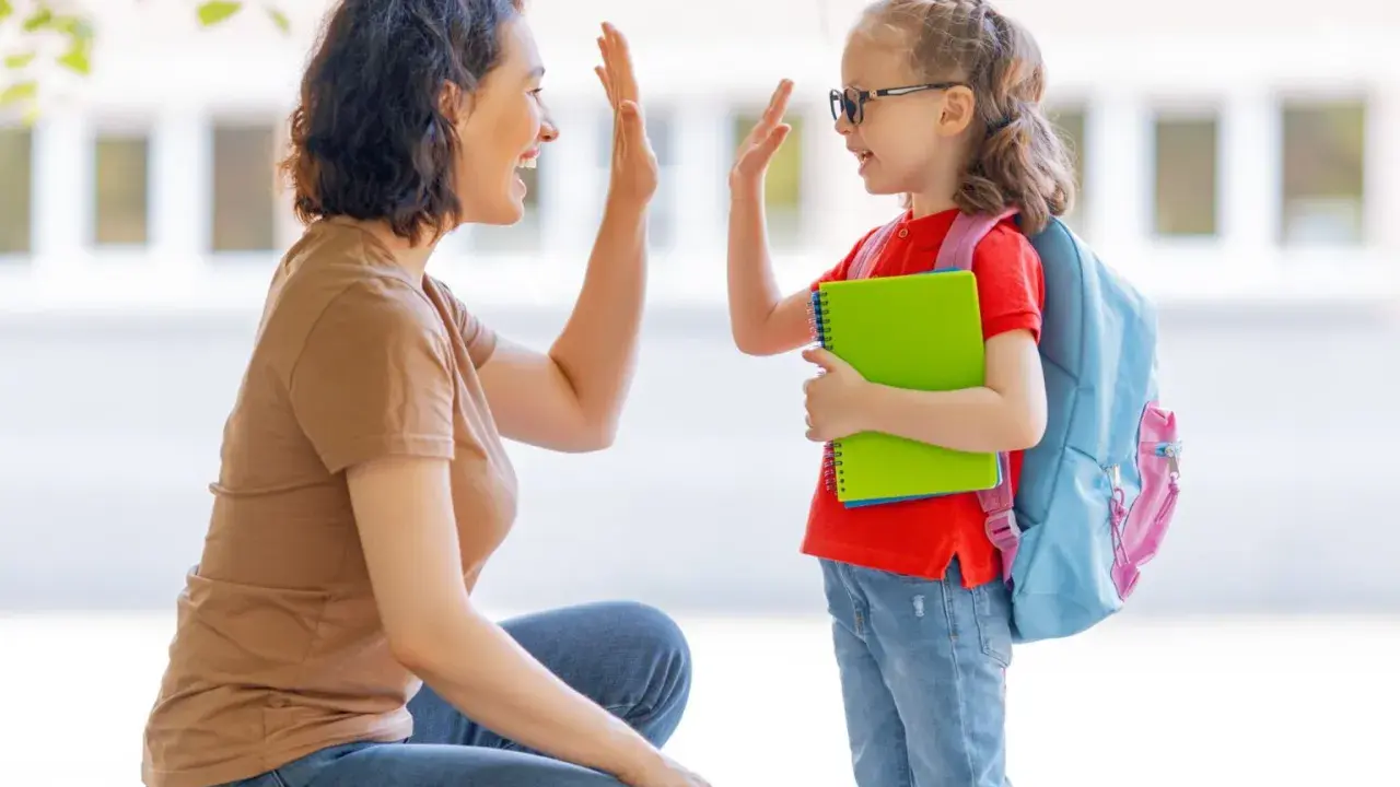 Madre y hija se dan un choque de manos, un momento de crianza positiva antes de ir a la escuela.