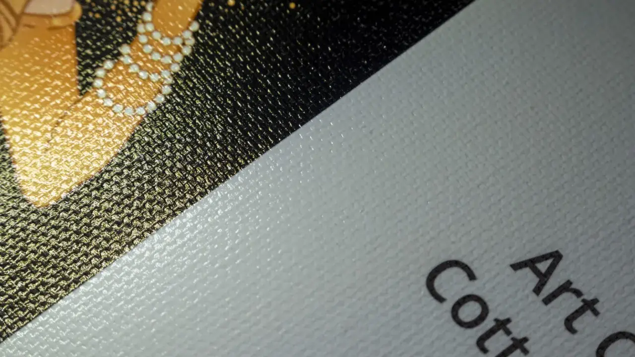 Fragment złocistego wzoru na czarnym tle, obok biały, fakturowany **canvas** z napisem "Art Cotton".