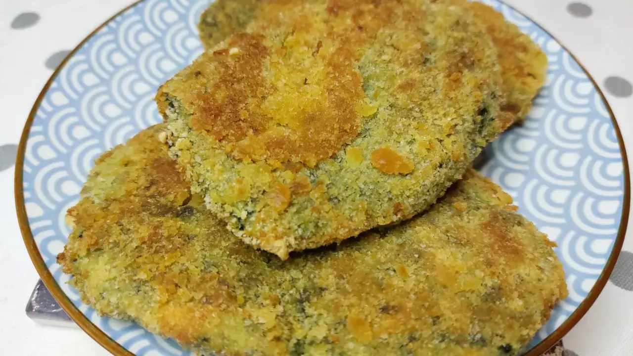 Tre spinacine fatte in casa, dorate e croccanti, servite su un piatto blu con decorazioni a onde.