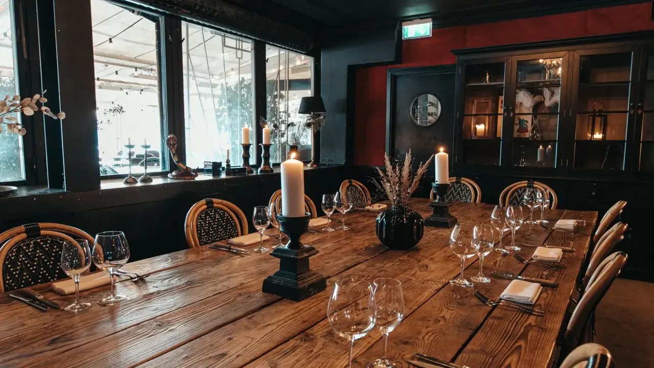 Ett elegant chambre séparée med ett långt träbord, dukat för middag med levande ljus och vinglas.