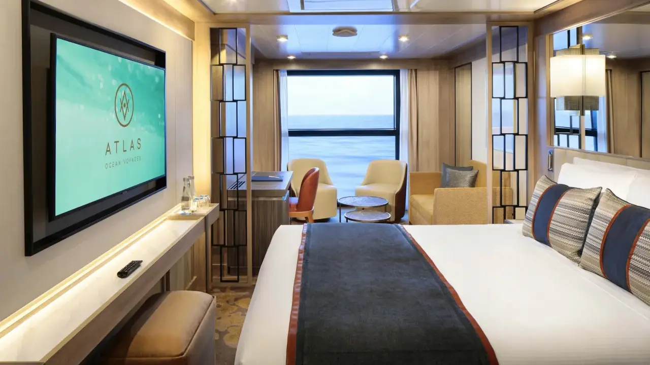 Interni lussuosi di una cabina garantita Costa Crociere con letto comodo, divanetti, scrivania e TV. Vista mare dalla finestra.