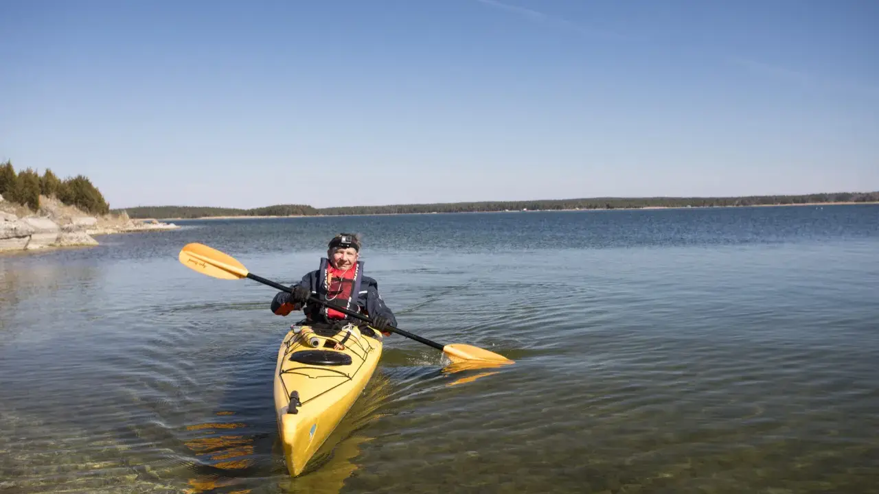 Man paddlar kanot på Gotland i klart vatten.