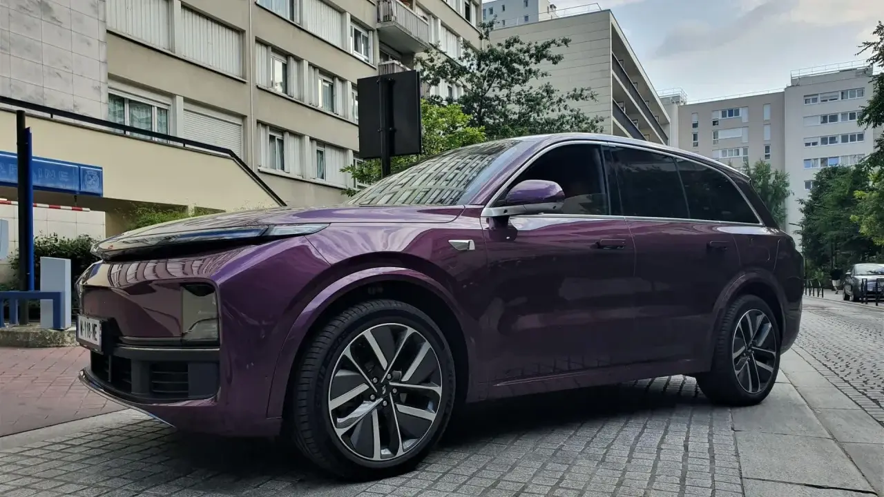 Une élégante li auto violette se gare devant des immeubles résidentiels.