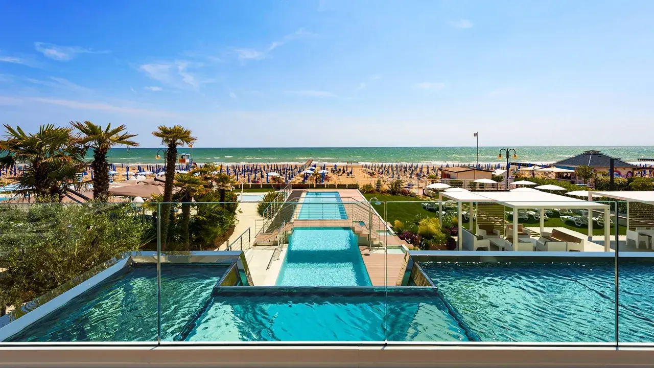 Lido di Jesolo atrakcje: baseny z widokiem na plażę, palmy i morze. Idealne miejsce na wakacje.