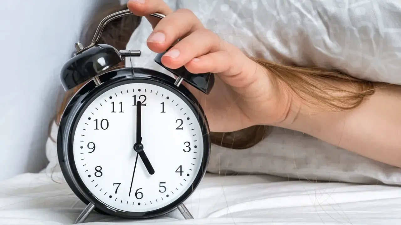 Ręka wyłącza budzik. Jest 5:00, a 0303 znaczenie tego czasu to nowy początek dnia.
