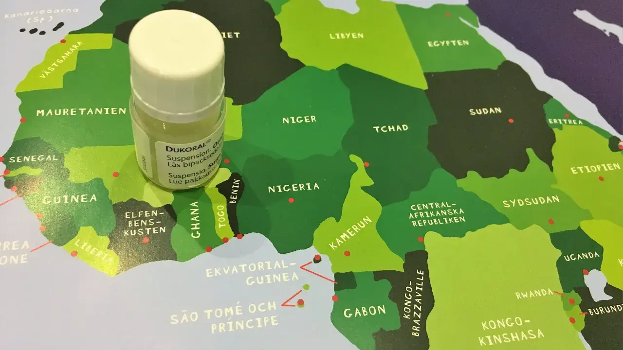En liten flaska Dukoral® står på en karta över Afrika, nära Guinea och Elfenbenskusten.