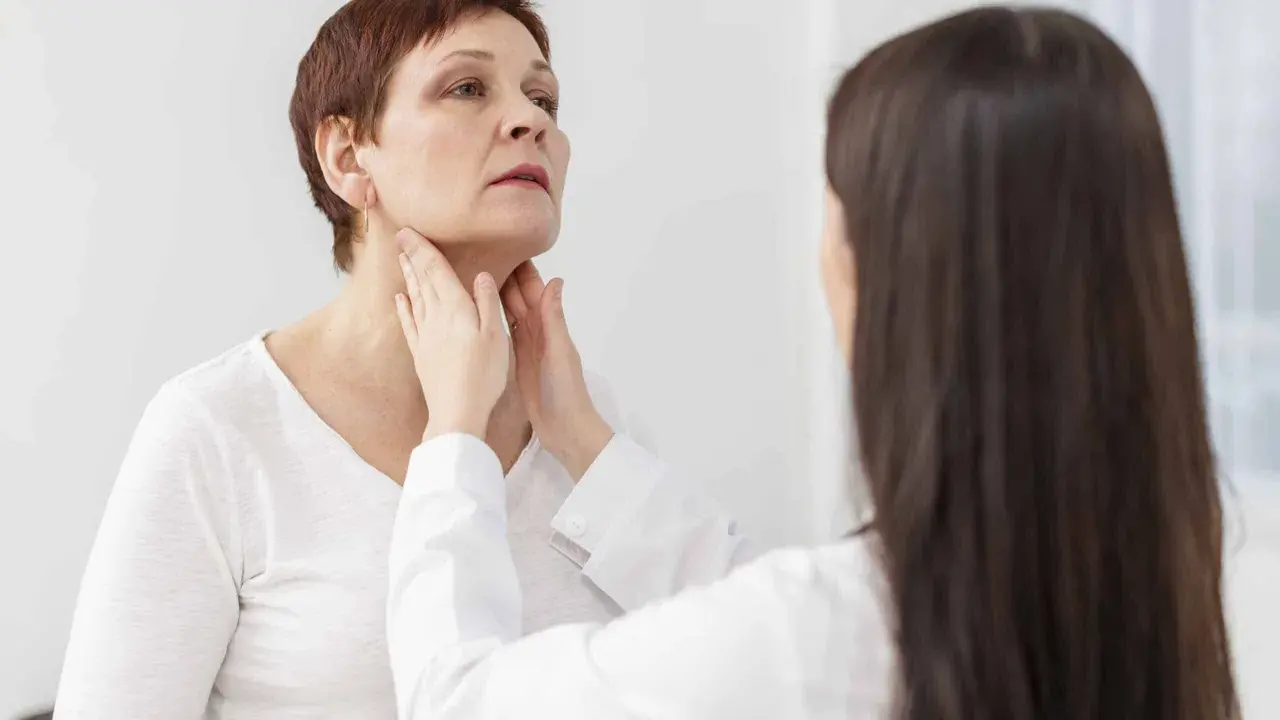 Medico esamina il collo di una paziente, possibile indicazione per una scintigrafia tiroidea.