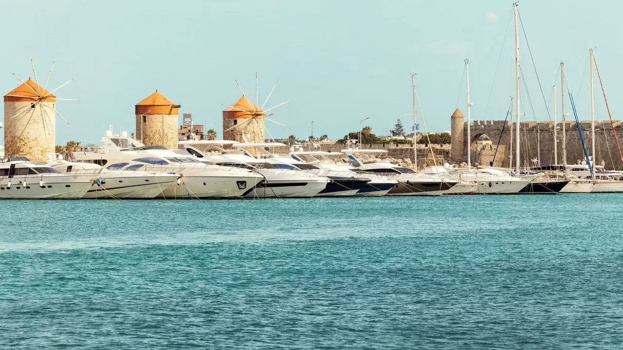 Väderkvarnar och lyxyachter i hamnen vid Rhodos stad. En historisk karta över Rhodos stad skulle visa denna vy.