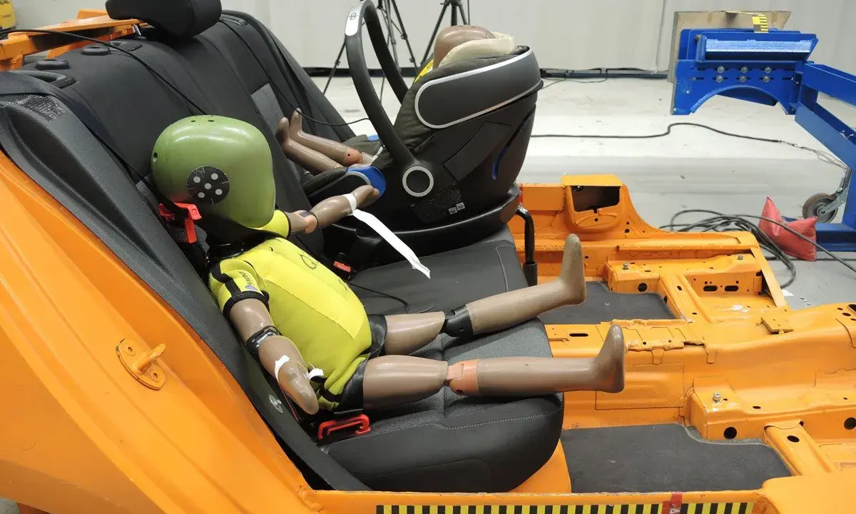 Maniquíes en un asiento de coche de prueba, preparándose para un test de seguridad según la normativa ECE R44/04.
