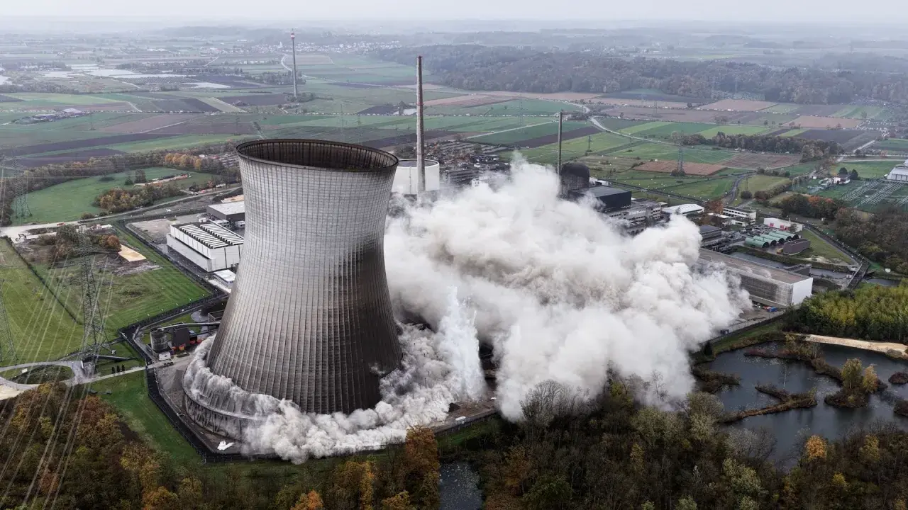 Ein Kühlturm stürzt ein, Staubwolken steigen auf. Ein Symbol für den **Atomausstieg Deutschland**.