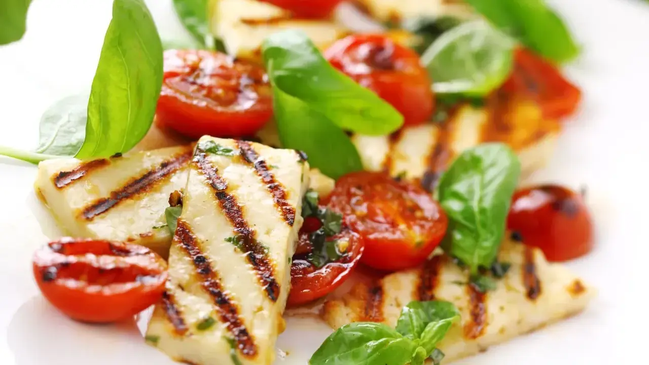 Grillowany serek halloumi z pomidorkami koktajlowymi i bazylią, apetyczna przekąska.