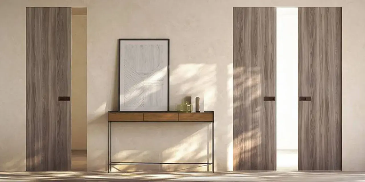 Porta in cartongesso con finitura in legno, minimalista e moderna, con un quadro astratto appeso sopra un tavolino.