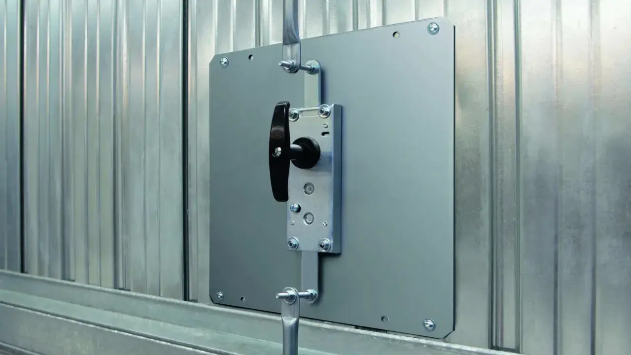 Système de verrouillage pour securiser porte garage. Poignée noire sur plaque métallique fixée sur porte en métal ondulé.