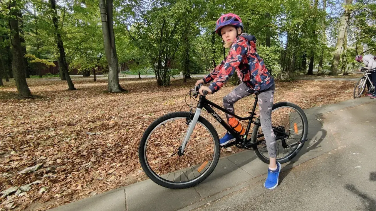Dziewczynka na rowerze, idealny rozmiar roweru dla 10 latka. Jesienny park, liście na ziemi.