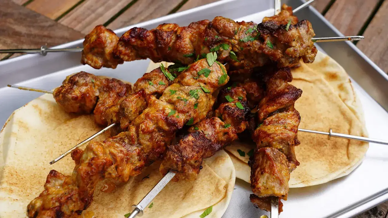 Saftige Schaschlik-Spieße, perfekt gegrillt, liegen auf Fladenbrot. Ein Genuss, der an ein gemütliches Essen im Dutch Oven erinnert.