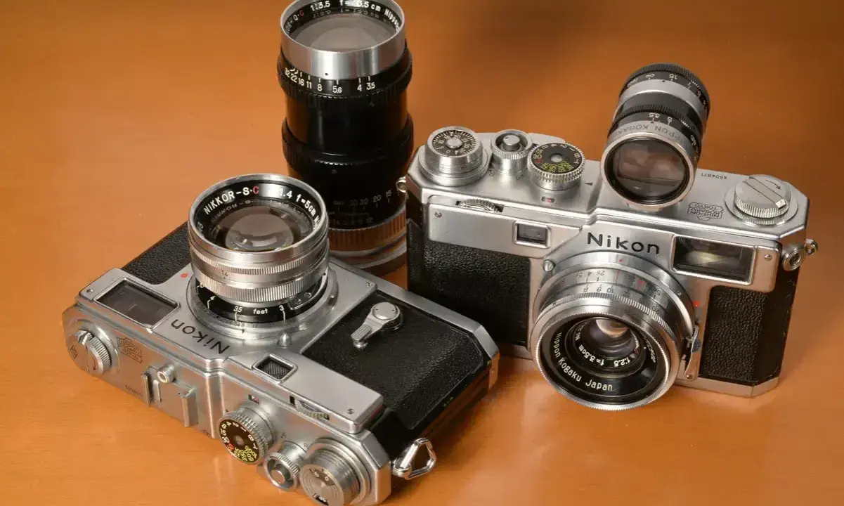 Kolekcja aparatów Nikon z obiektywami. Dwa modele Nikon z lat 50. i 60. XX wieku, każdy z innym obiektywem Nikkor.