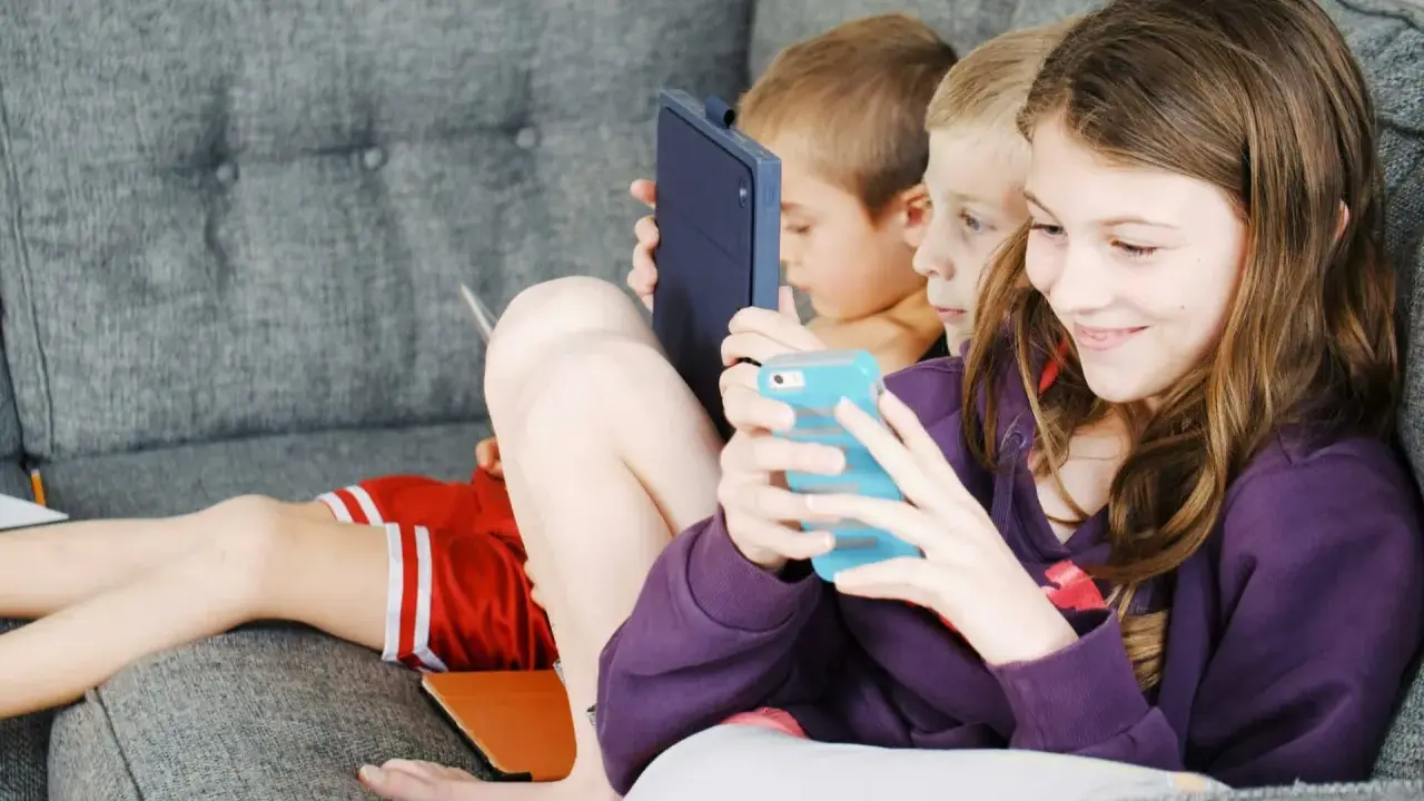 Trois enfants absorbés par leurs écrans, un rappel pour un atelier sensibilisation aux écrans.