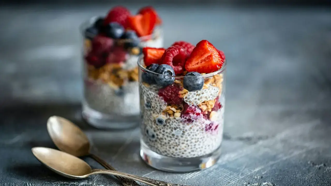 Två glas med chiapudding, toppade med bär och granola. Ett perfekt chiapudding recept för en hälsosam frukost eller mellanmål.