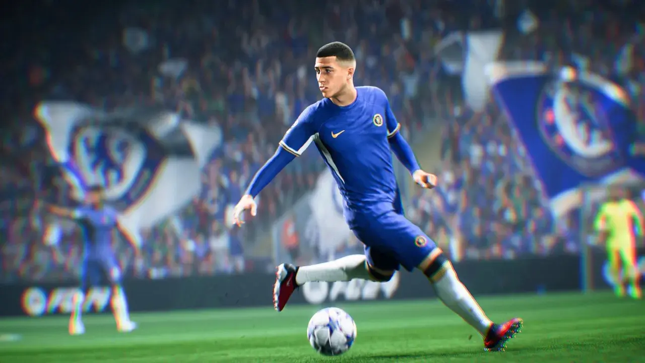 Piłkarz w niebieskiej koszulce Chelsea drybluje piłką na boisku, gotowy do strzału w grze FIFA 2k.