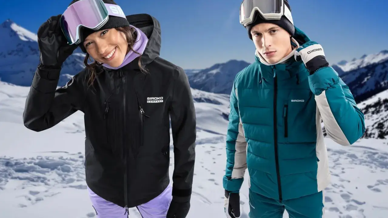 Para narciarzy w górach. Ona w czarnej kurtce hardshell, on w turkusowej kurtce softshell.