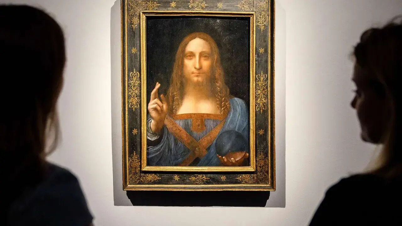 Two viewers admire Leonardo da Vinci's "Salvator Mundi," the most expensive piece of art ever sold, in its ornate frame.