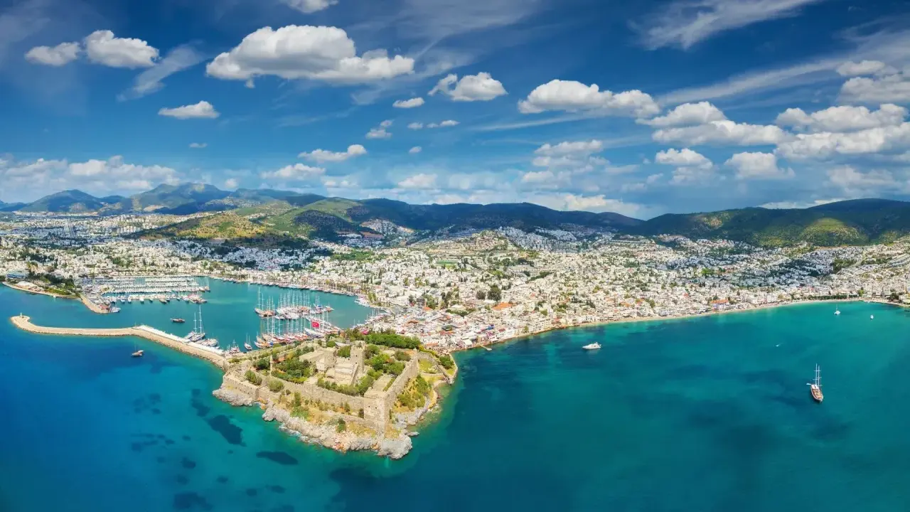 Widok na zamek i zatokę pełną łodzi. Czy to Bodrum, czy Alanya? Piękne turkusowe morze i białe domy na wzgórzach.