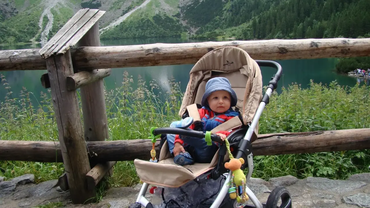 Niemowlak w wózku podziwia Tatry. Piękny widok na jezioro i góry.