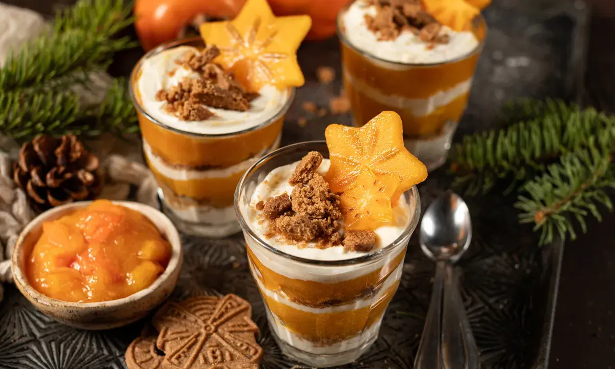 Schichtdessert mit Kaki, Sahne und Keksbröseln, garniert mit Sternfrucht. Ein festliches Kaki-Dessert.