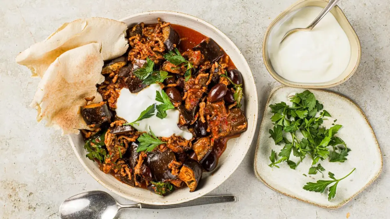 Délicieuse recette aubergine viande hachée, servie avec du pain pita, une cuillère de yaourt et du persil frais.