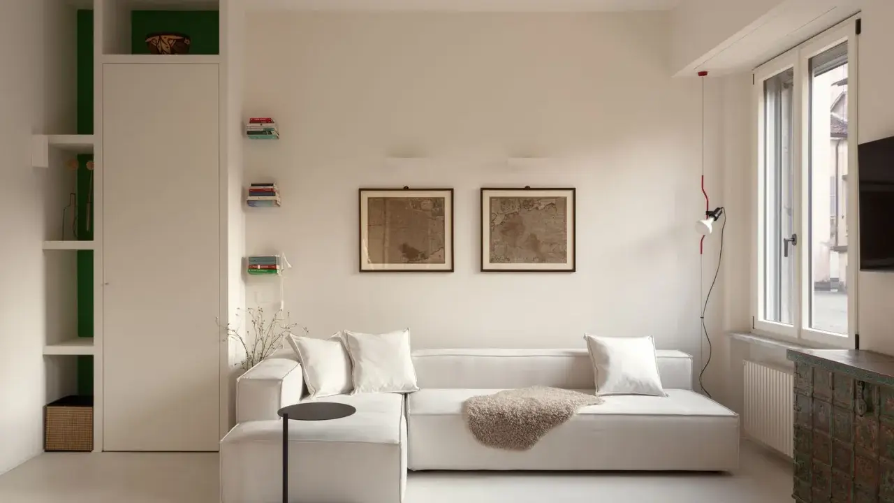 Soggiorno moderno: divano bianco, quadri antichi e libreria a giorno. Idee su come arredare con stile e funzionalità.