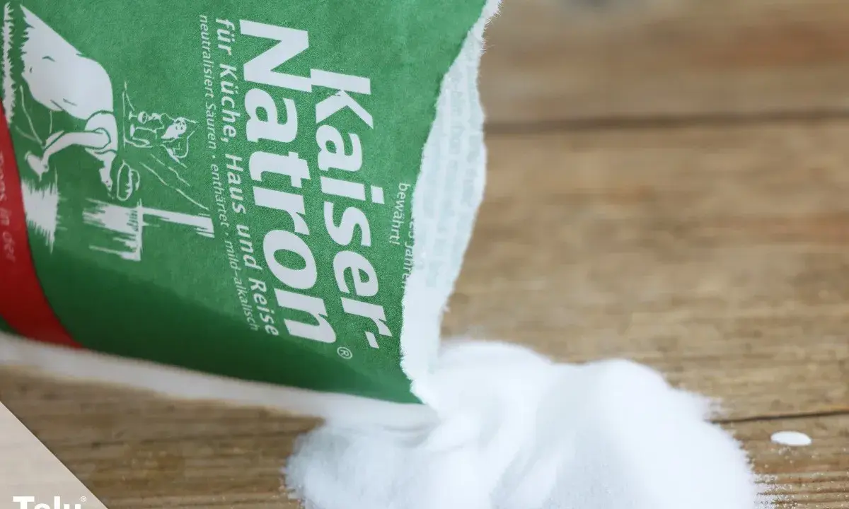 Kaiser Natron wird zum Teppich reinigen mit Natron verwendet. Das weiße Pulver liegt auf Holz.