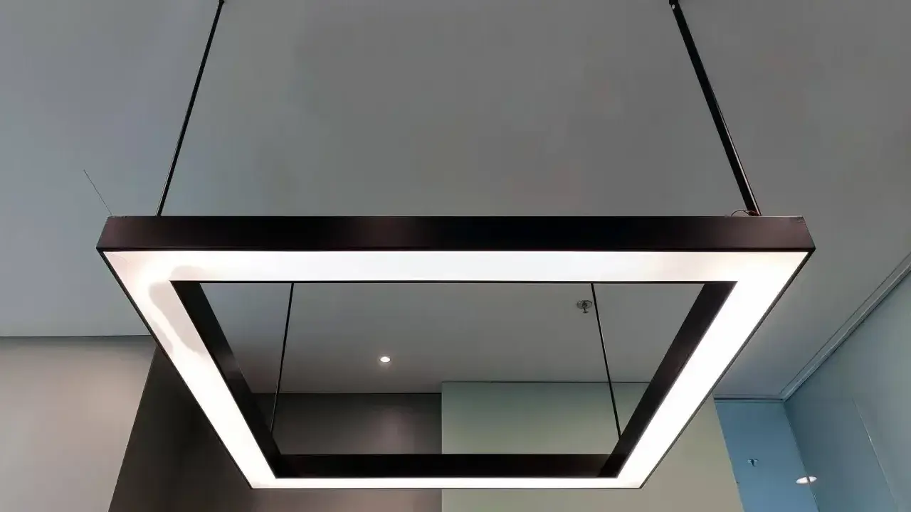Nowoczesna podsufitka led w kształcie kwadratu, zawieszona na cienkich linkach, tworzy minimalistyczną i elegancką przestrzeń.