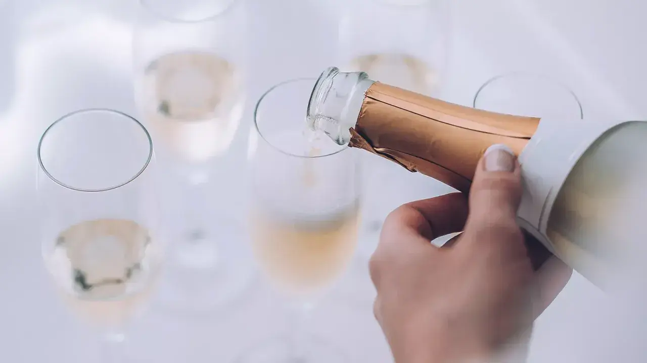 Eine Hand gießt Champagner in ein Glas. Die Bläschen steigen auf und lassen erahnen, wie gut der Champagner schmeckt.