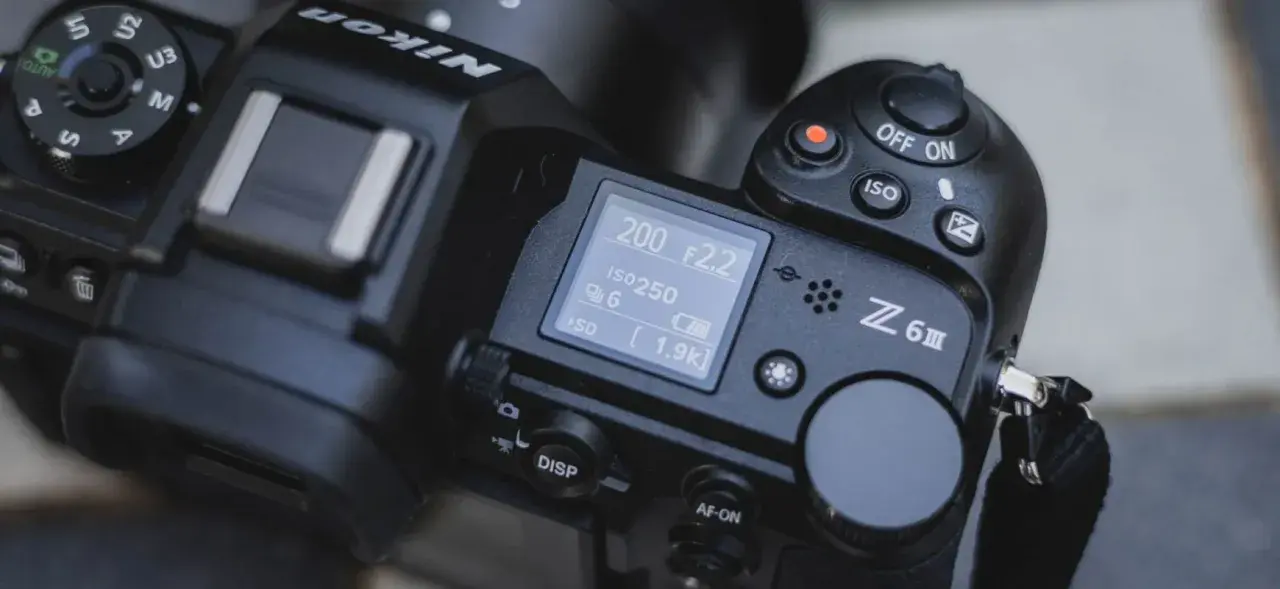 Górna część aparatu Nikon Z6 III z widocznym ekranem LCD, pokrętłem trybów i przyciskiem nagrywania.