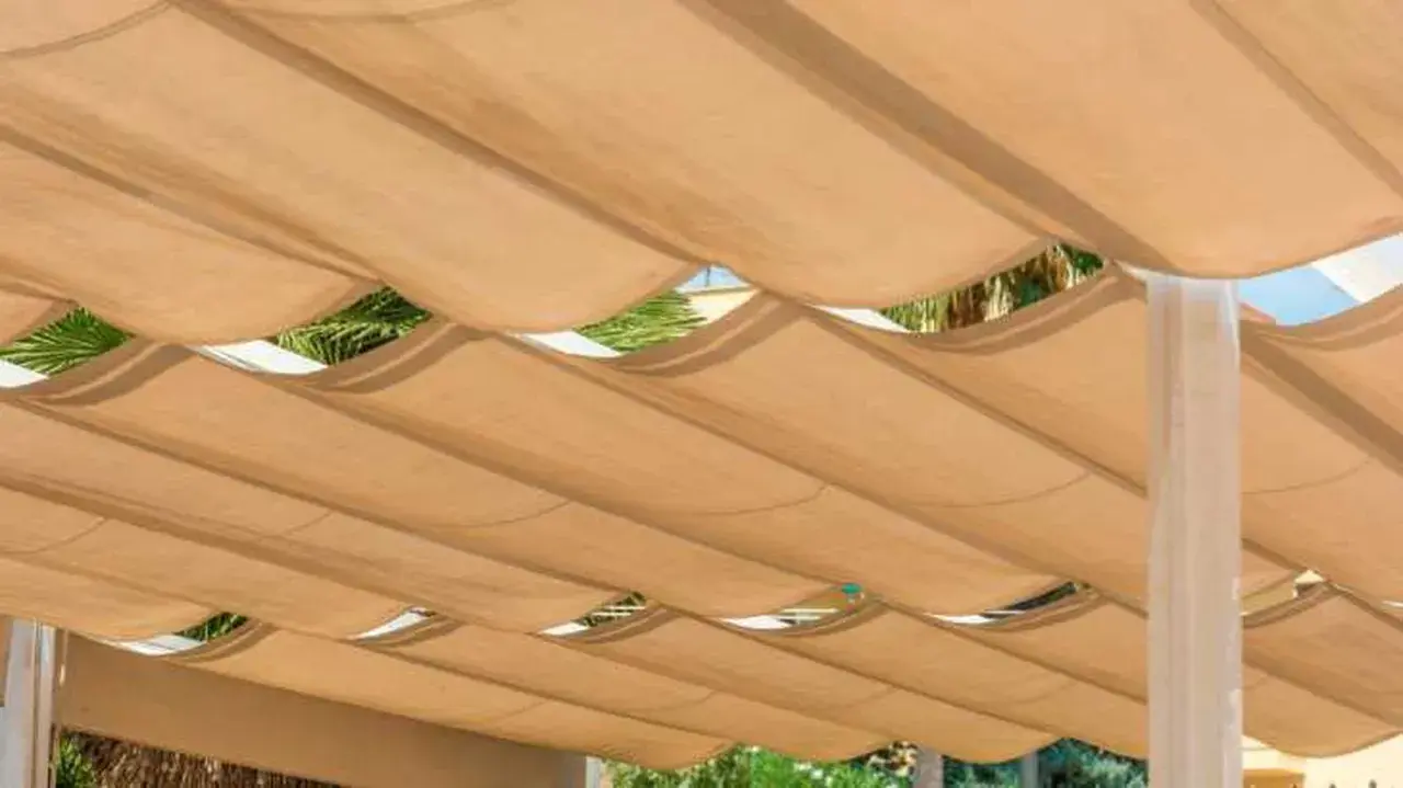 Techar patio económico con toldo de tela beige ondulado, creando un espacio sombreado y fresco.