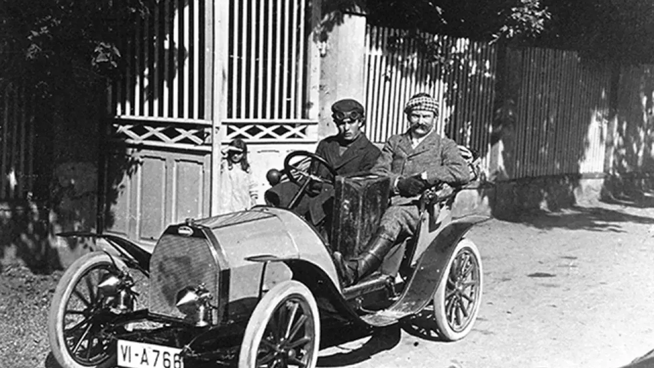 Zwei Männer in einem Bugatti, der aus Molsheim stammt, fahren durch eine sonnige Straße.