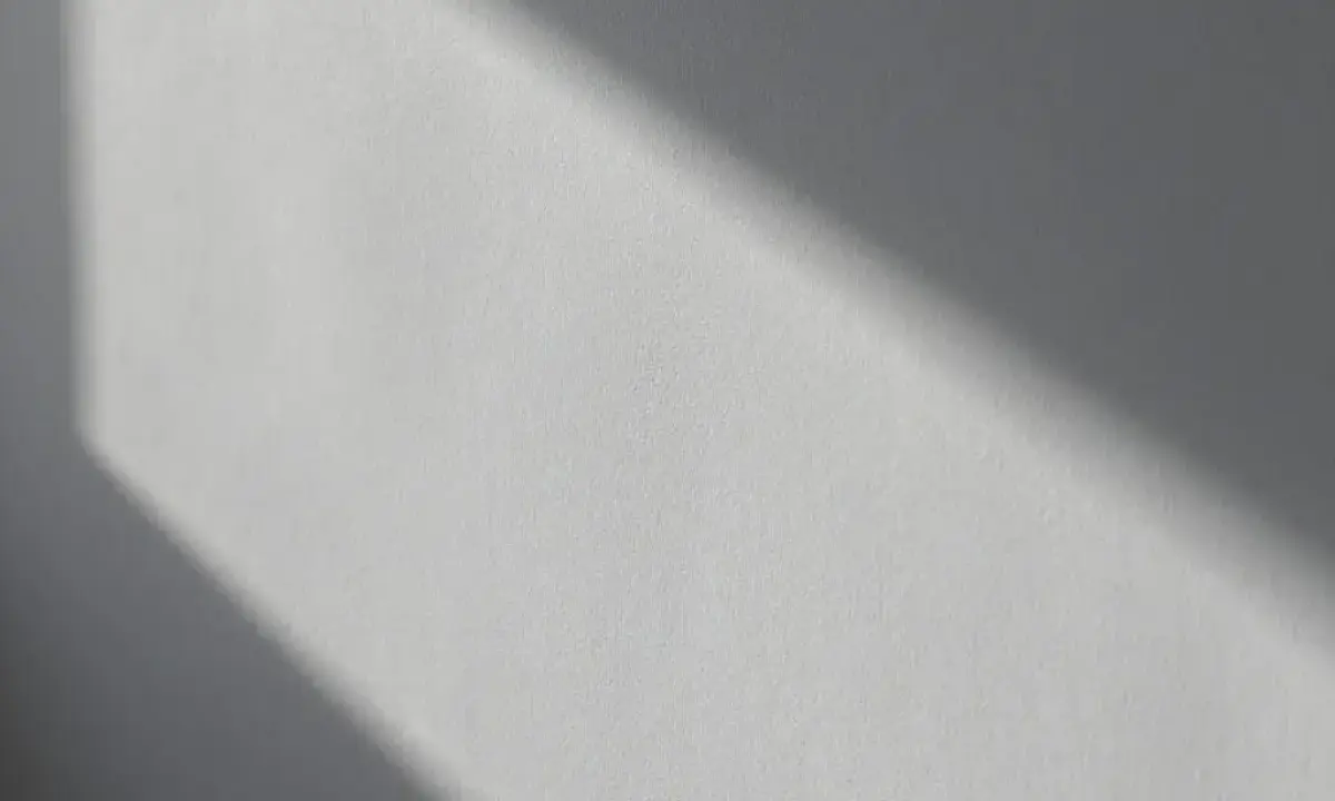 Światło podkreśla nierówności na elewacji, tworząc cień o geometrycznym kształcie.